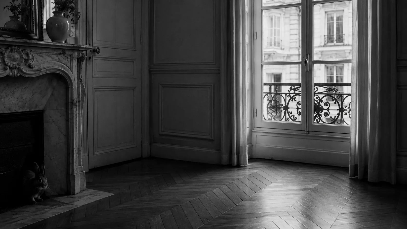 Gros plan noir et blanc de l'œil et du museau d'un lapin émergeant de l'ombre sous un meuble