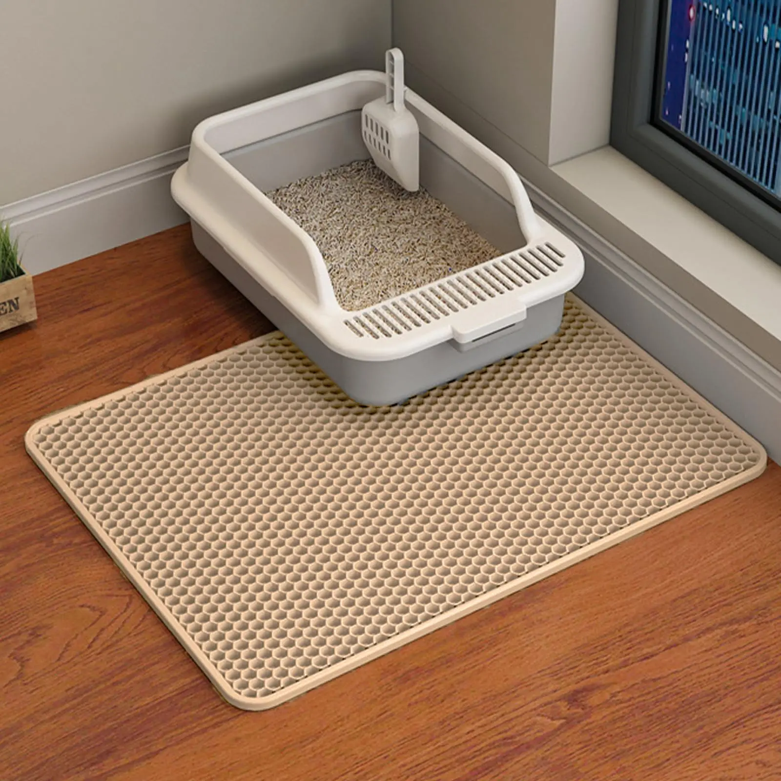 Tapis de litière beige alvéolé devant un bac à bords hauts, sur parquet