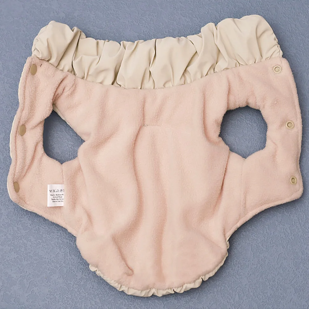 Intérieur d'un manteau matelassé beige doublé de polaire rose, avec boutons-pression sur les côtés