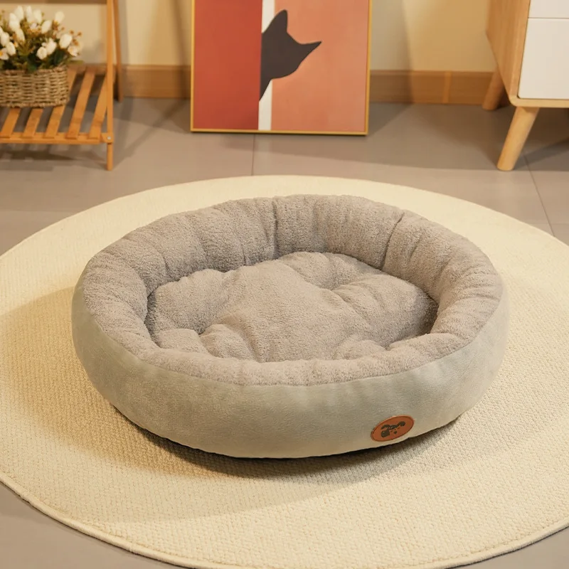 Panier rond en peluche grise posé sur un tapis rond beige, devant un cadre orange