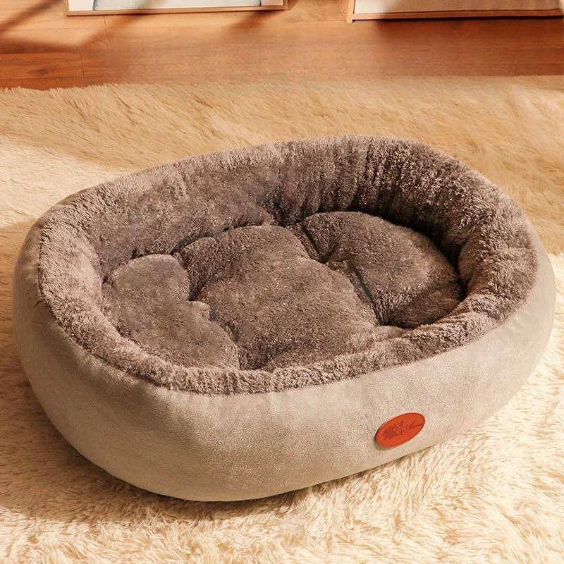 Panier rond pour animal en peluche taupe à bords rembourrés, posé sur un tapis crème