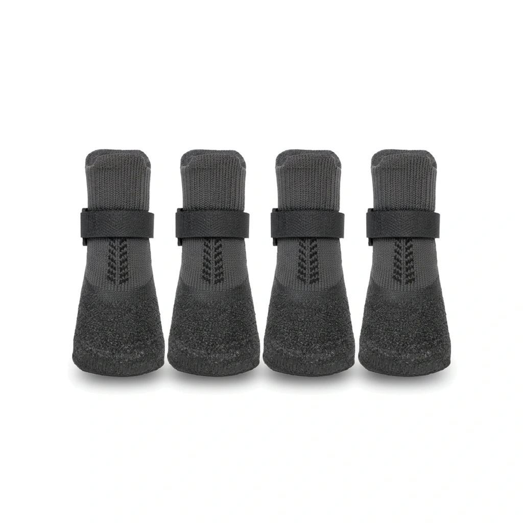 Quatre chaussettes de protection noires pour pattes de chien, avec sangle à scratch et semelle texturée, sur fond blanc