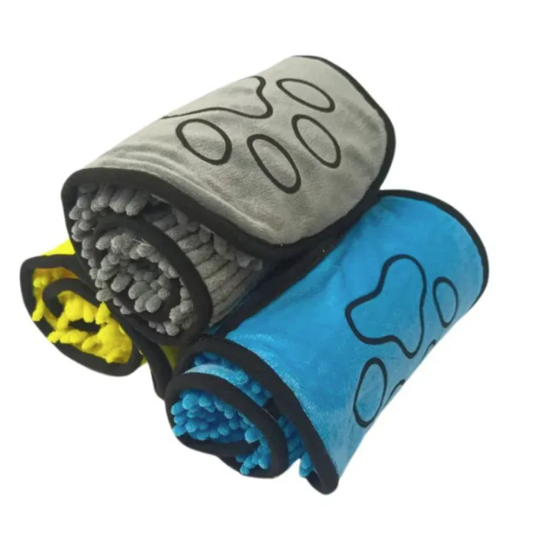 Trois serviettes de séchage roulées, grise, bleue et jaune, avec leur patte brodée sur fond blanc
